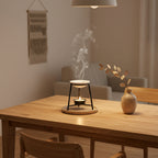 Noire geurbrander met brandend waxinelichtje in een minimalistisch interieur
