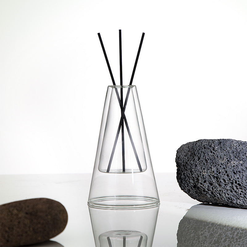 STUDIO NOÉRA Élane clear borosilicate glass diffuser bottle with a tall geometric design and included reed sticks.