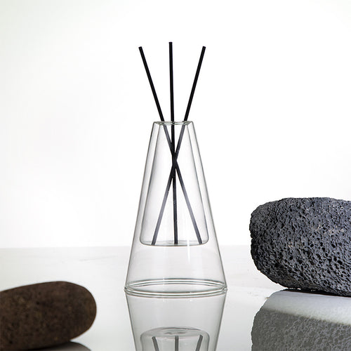 STUDIO NOÉRA Élane clear borosilicate glass diffuser bottle with a tall geometric design and included reed sticks.